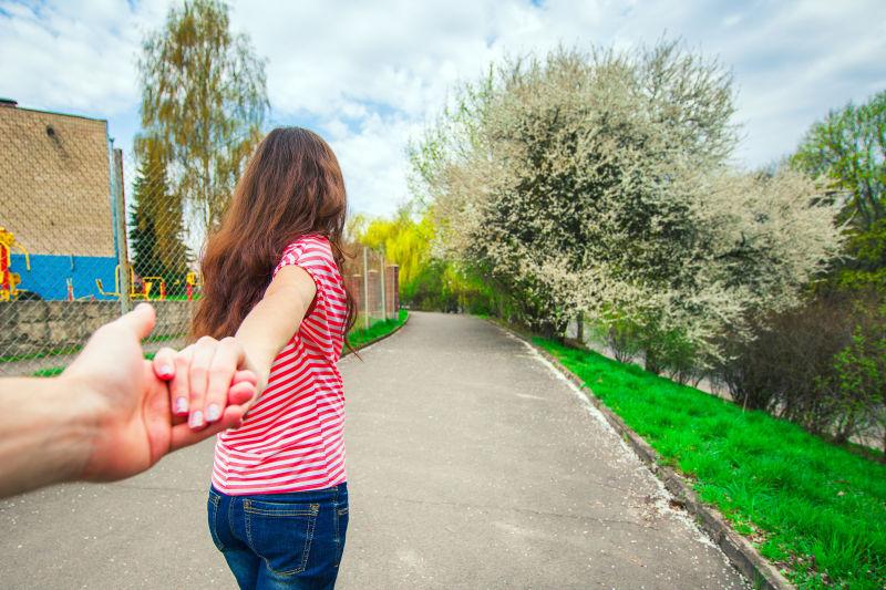 一个女孩手牵恋人的手去旅行