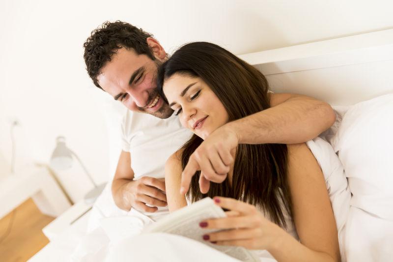 床上英俊可爱的年轻夫妇一起看书