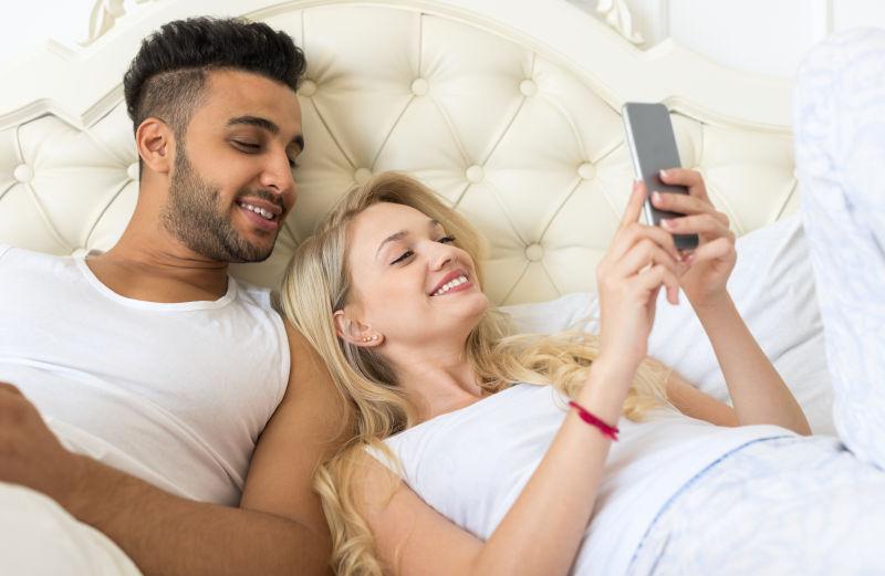 小两口躺在床上微笑着看手机