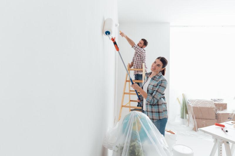 年轻的幸福夫妇用油漆辊涂抹新房子