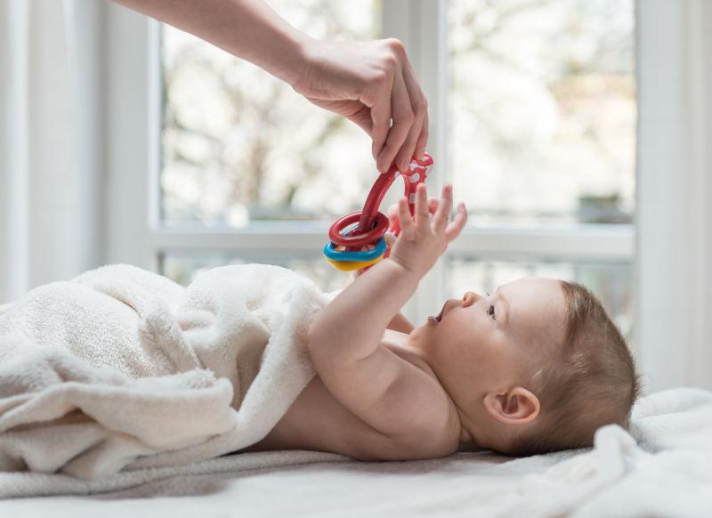 躺在床上伸手接玩具的可爱的小宝贝