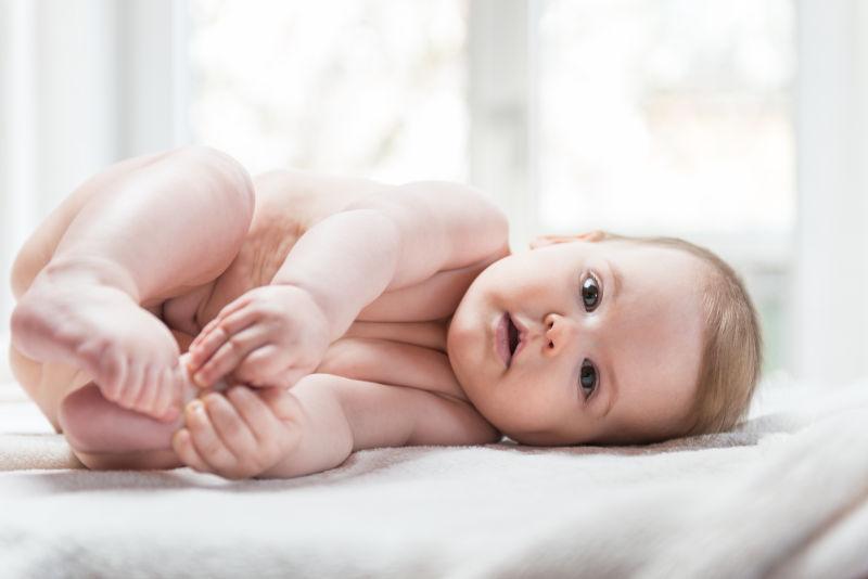 侧躺在床上刊社镜头抱着小脚丫的小婴儿