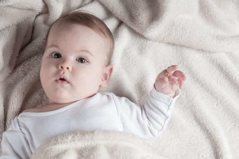 躺在床上盖着毛毯看着镜头的小女孩