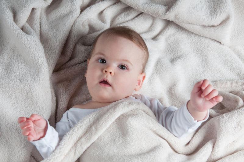 躺在白色的毛毯上的小婴儿肖像