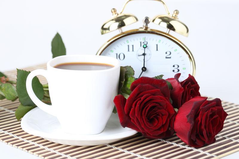 桌子上的闹钟和咖啡杯还有玫瑰花