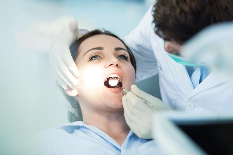 牙医正在用口镜给病人检查牙齿