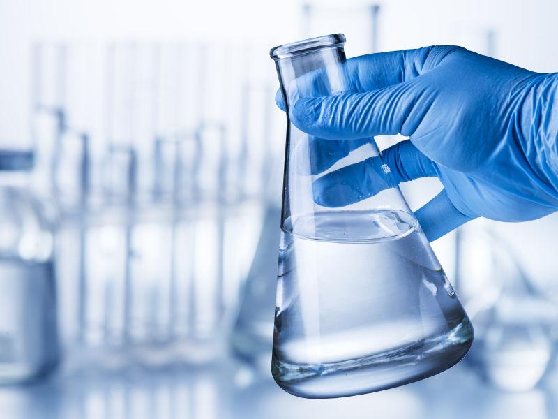 戴着手套的实验师手里的实验室烧杯