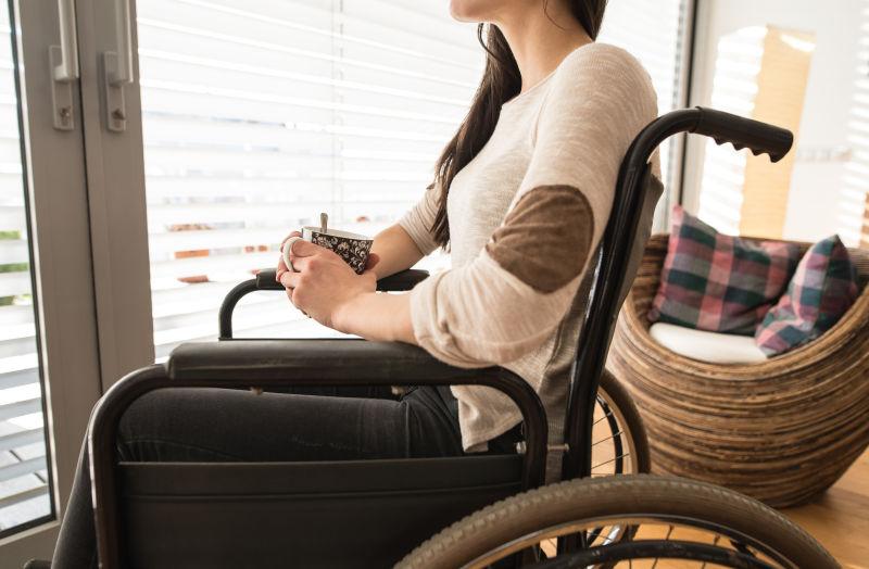 在客厅里坐在轮椅上的年轻残疾妇女