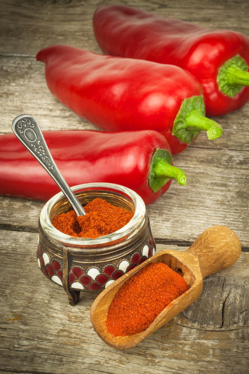 木桌上的三颗红辣椒与辣椒粉