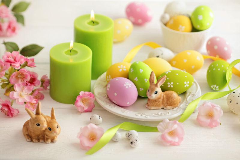 白色桌上的蜡烛和餐盘里的复活节彩蛋