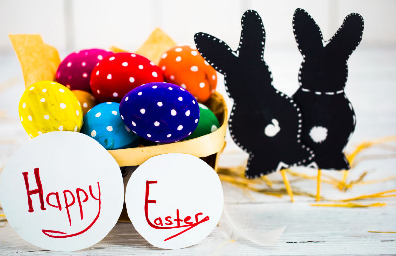 白色桌上的木筐里的复活节彩蛋和祝福兔纸