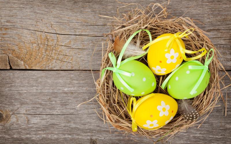 老旧木板上的草窝里的复活节彩蛋