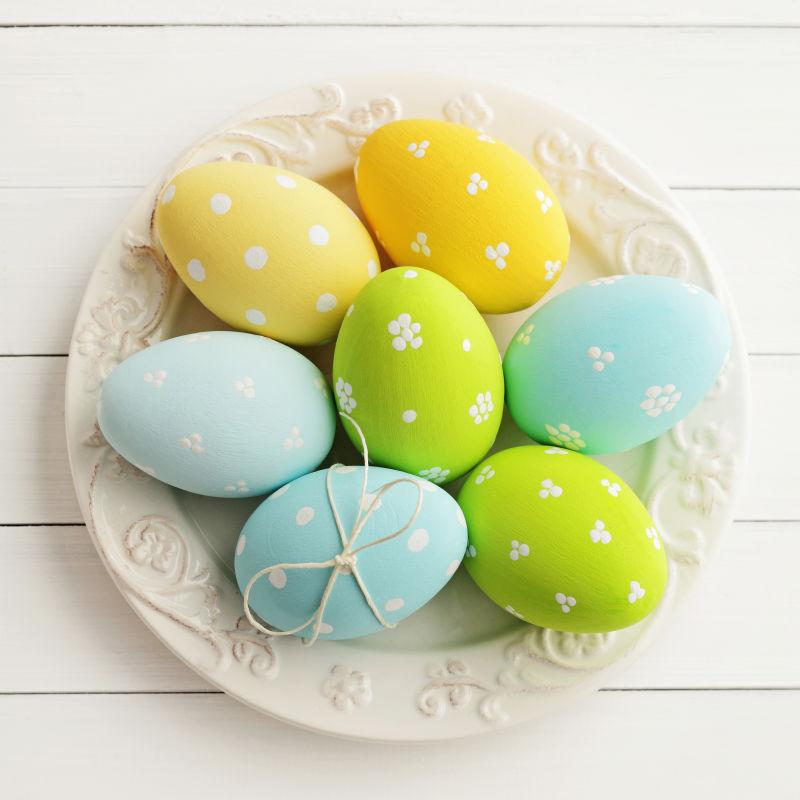 白色木桌上白色盘子里的复活节彩蛋