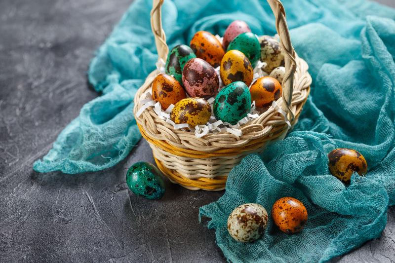 有丝巾的灰色桌上的篮子里的复活节鹌鹑蛋