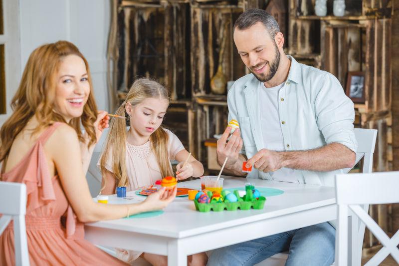 快乐的家庭坐在桌子上一起画复活节彩蛋