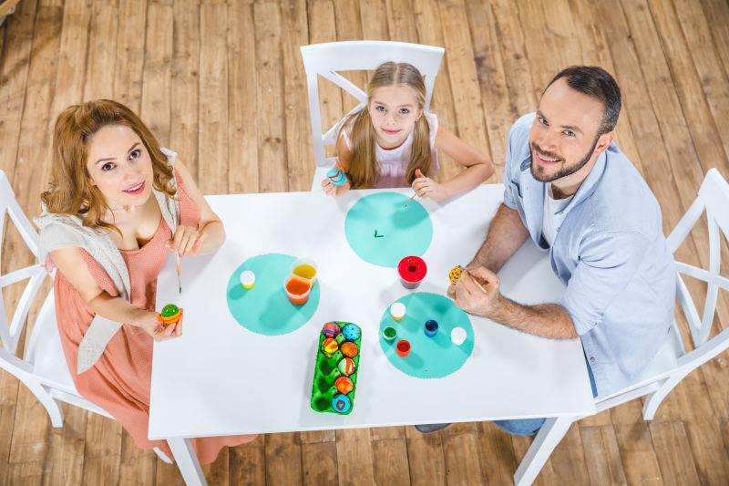 幸福家庭在桌面彩绘复活节彩蛋的顶视图