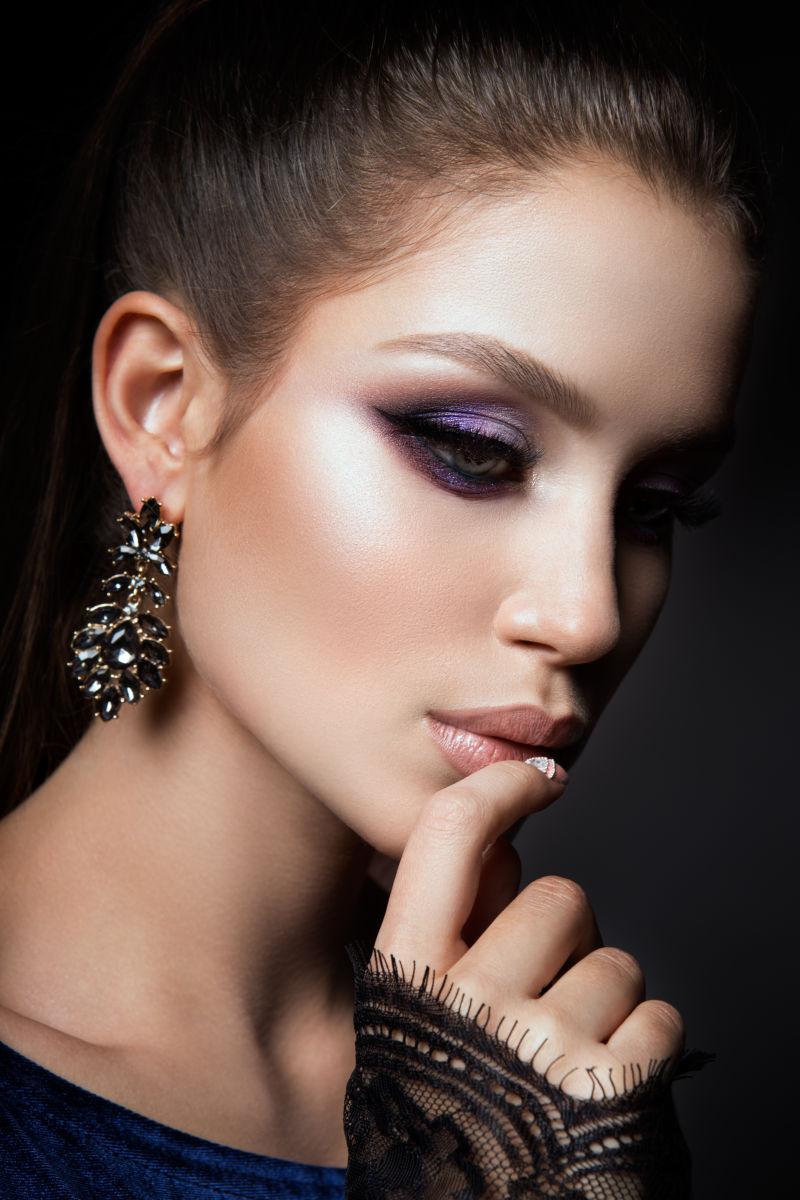 黑色背景上手指放在嘴唇上的年轻美女