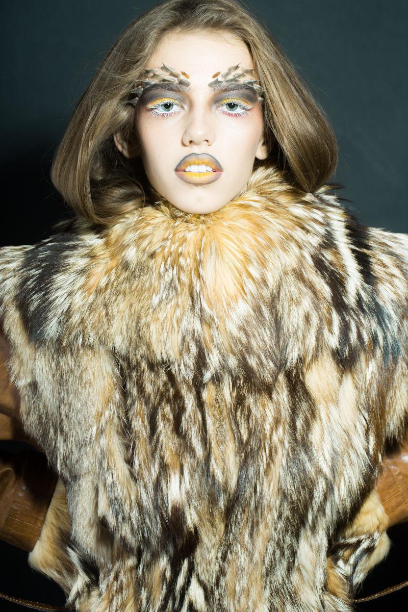 拥有金色的动物猴子化妆的穿着裘皮大衣的美丽的野生年轻女子