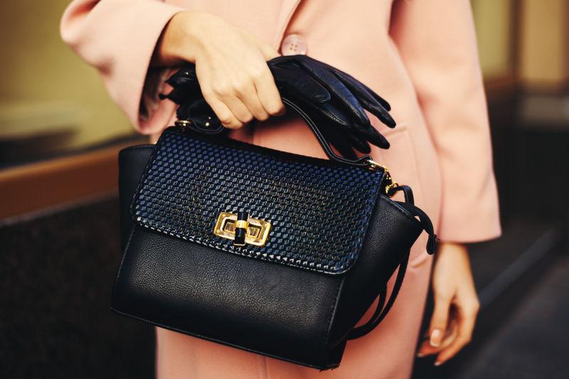 在时尚女性手中的黑色手袋特写