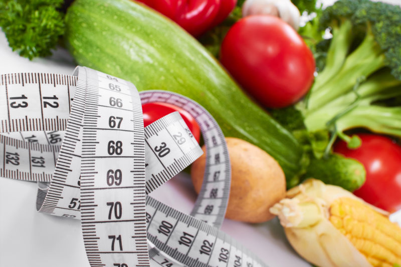 白色桌上的皮尺和新鲜健康蔬菜