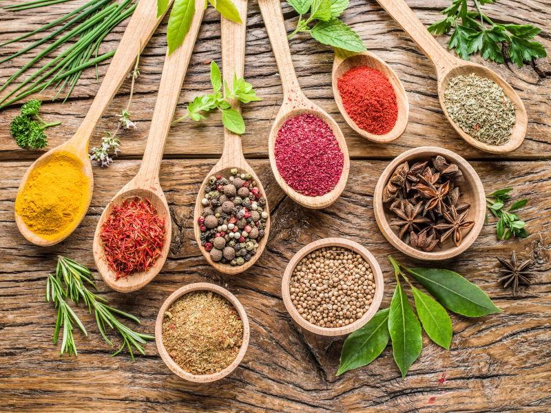 木桌上木勺上五颜六色的香料