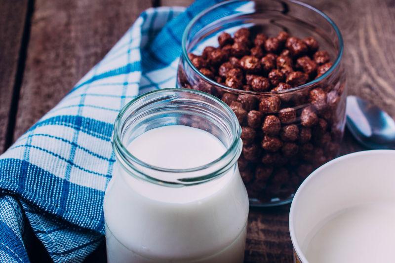 一杯牛奶与一瓶巧克力球在木桌上