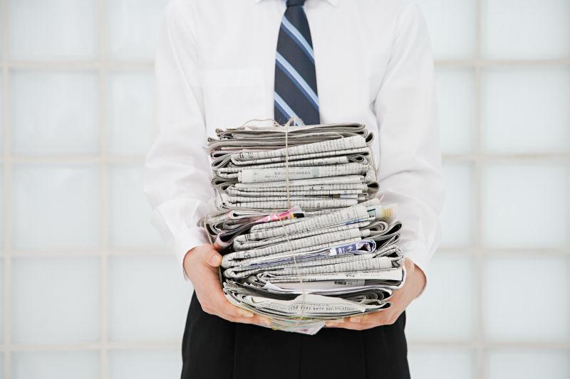 一个手里拿着一摞报纸的人