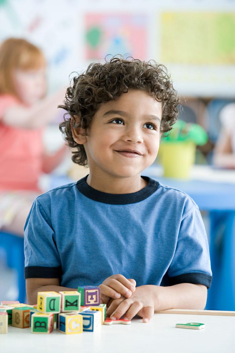 坐在课桌前玩积木的男孩