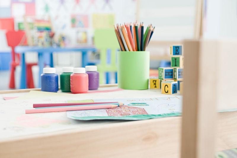 放在木桌上的颜料桶和彩色铅笔