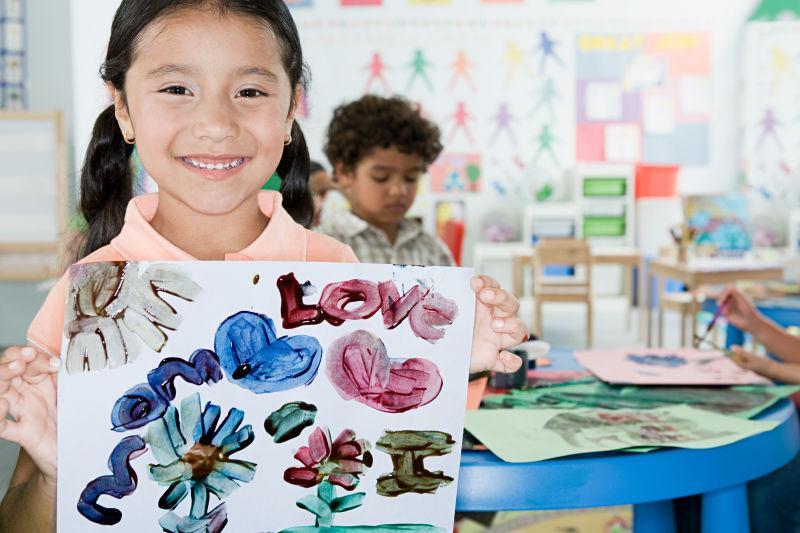 展示自己绘画作品的高兴地小女孩