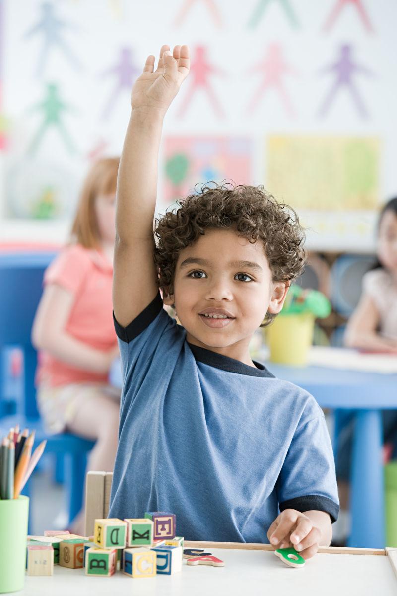 坐在教室内部高举双手的男孩子