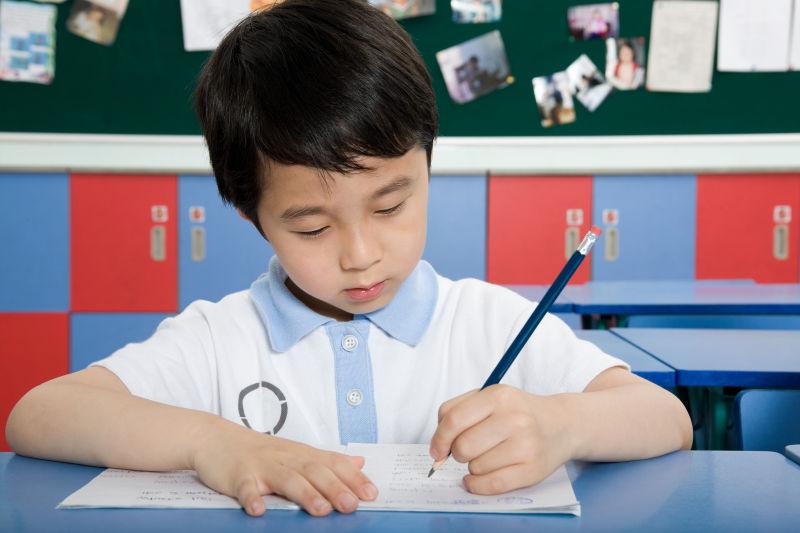 教室内认真写字的男孩