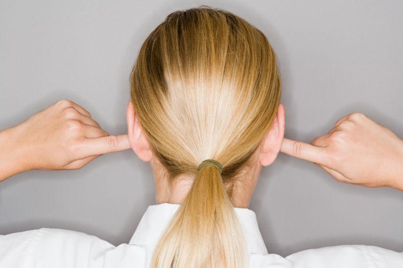 双手堵住耳朵的金发美女背面