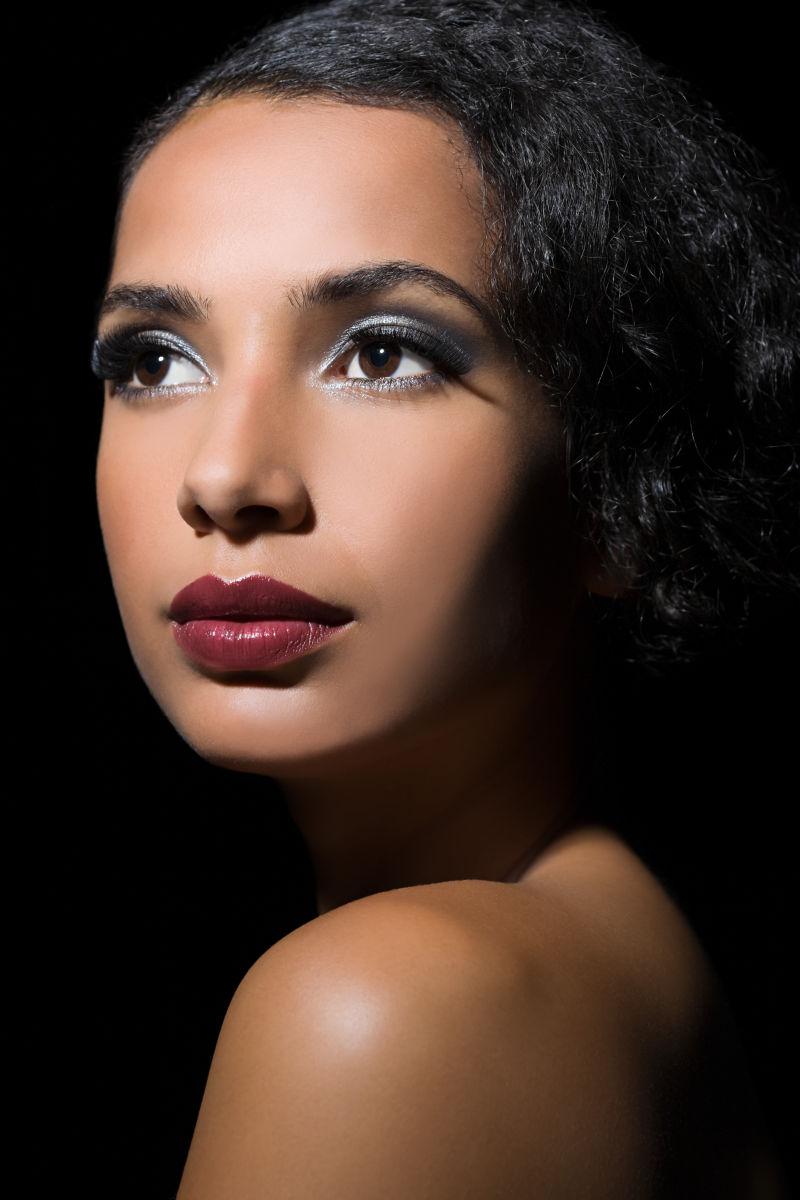 黑色背景下涂着口红的美女