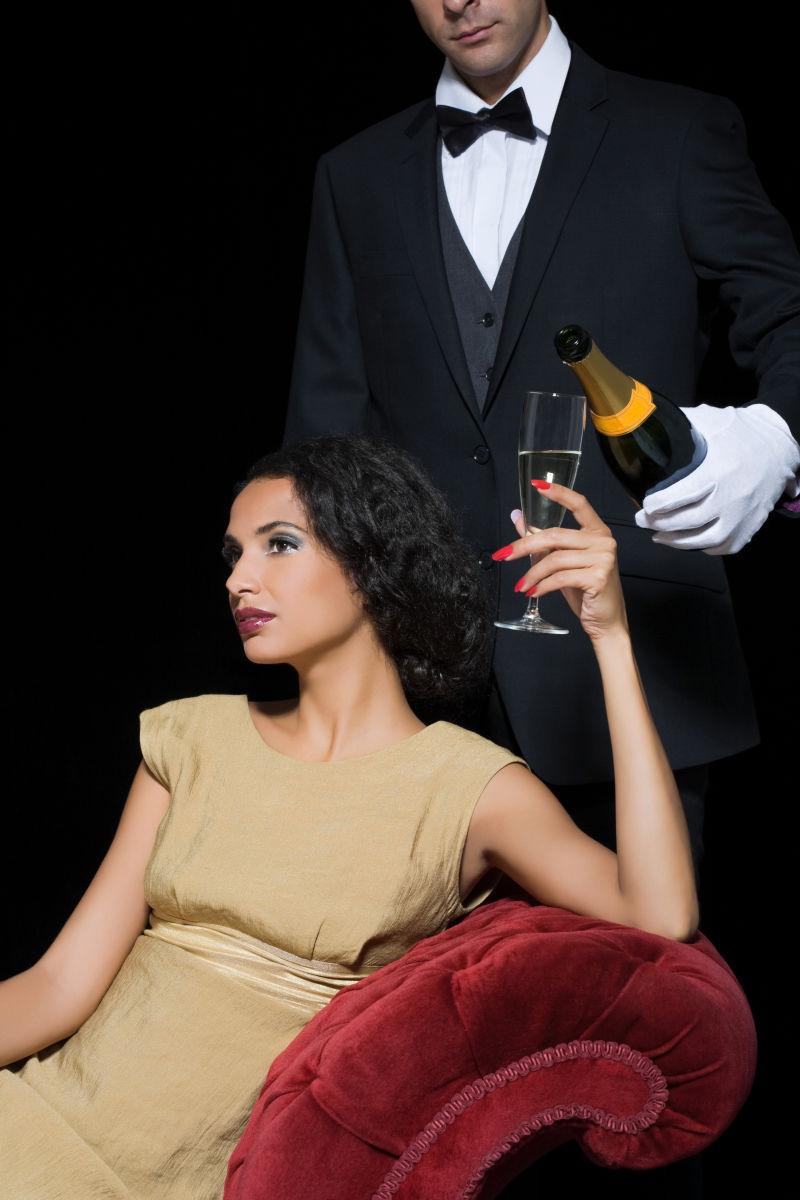 美女坐在沙发上享受男仆倒香槟的待遇