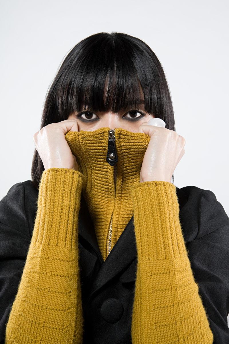 白色背景下穿着黄色和黑色外套的黑发亚裔美女