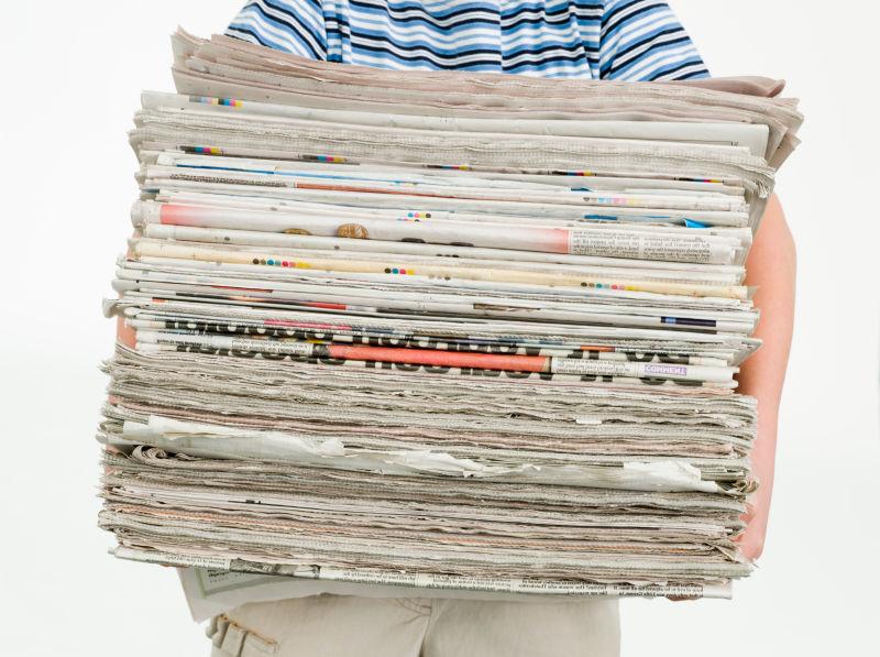 拿着一摞报纸的男孩