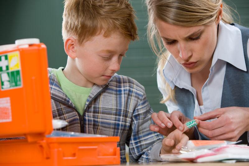 受伤的男孩子老师为他帖创口贴