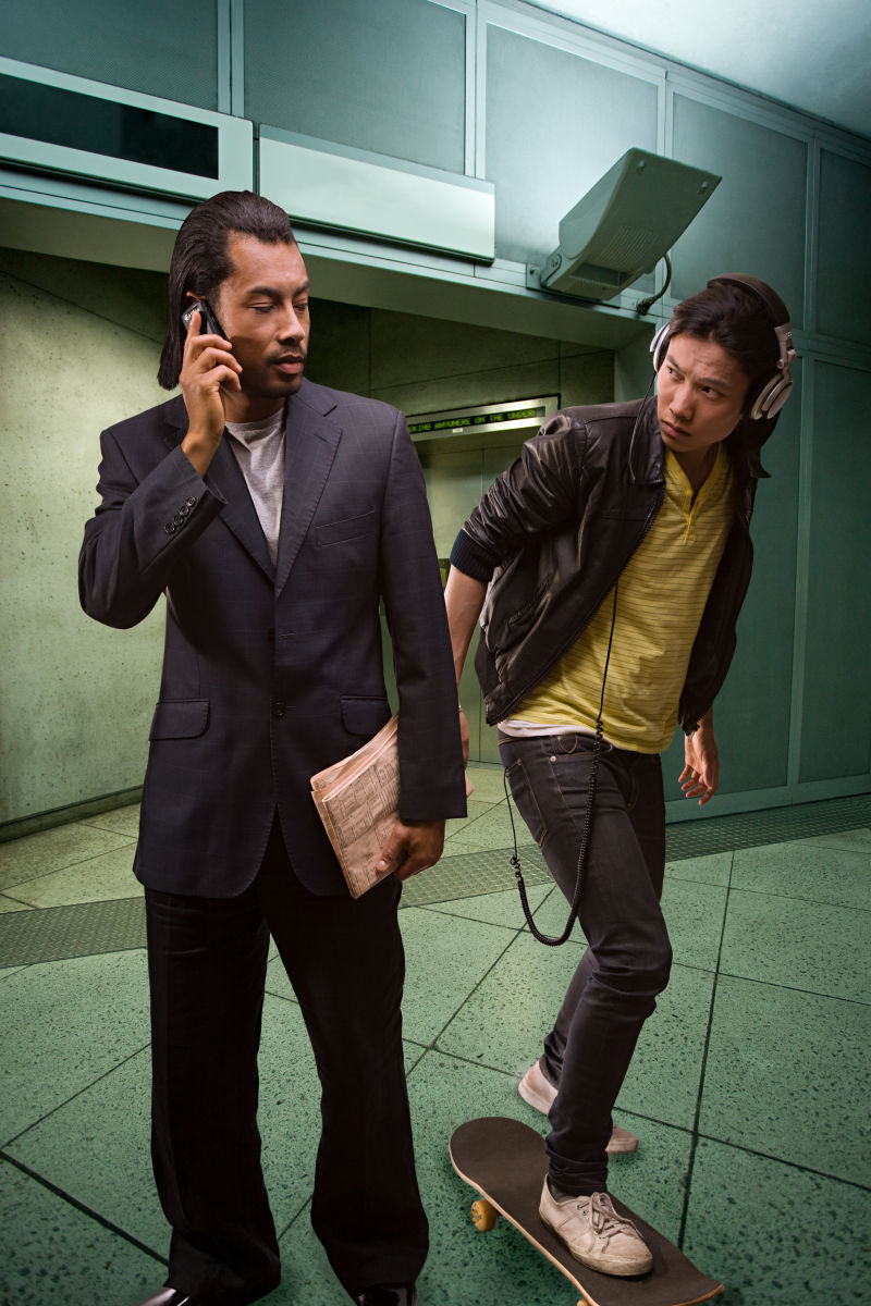 地铁里玩滑板戴耳机的男人和打电话的商人