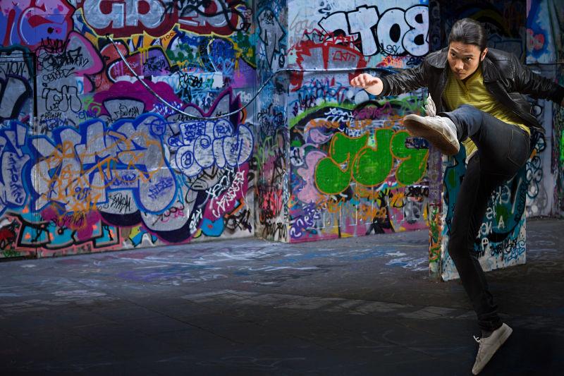 在街头涂鸦墙前跳跃的男人