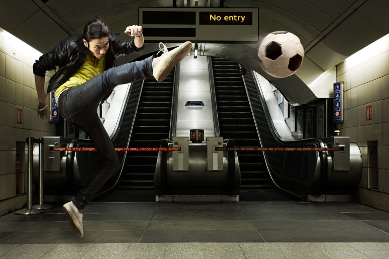 在地铁站踢足球的男人