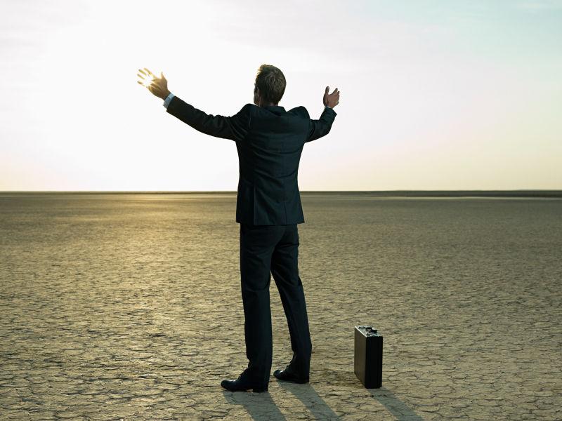 干旱土地上举起双臂的商人