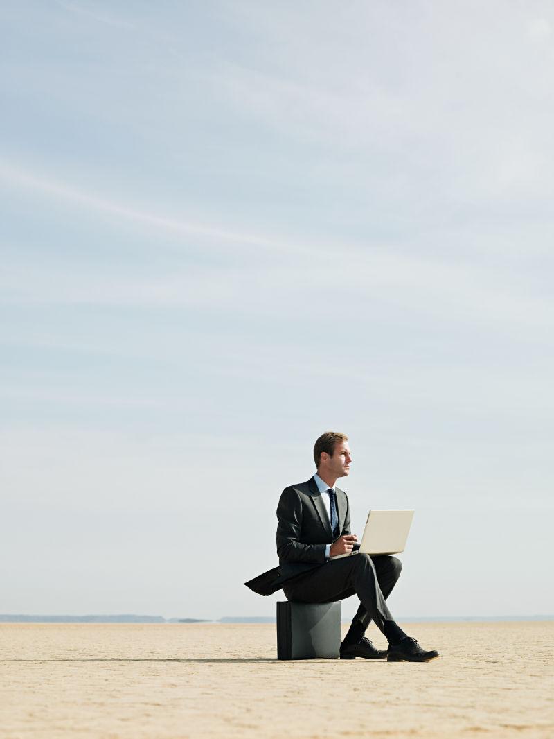 干旱土地上使用笔记本的商人