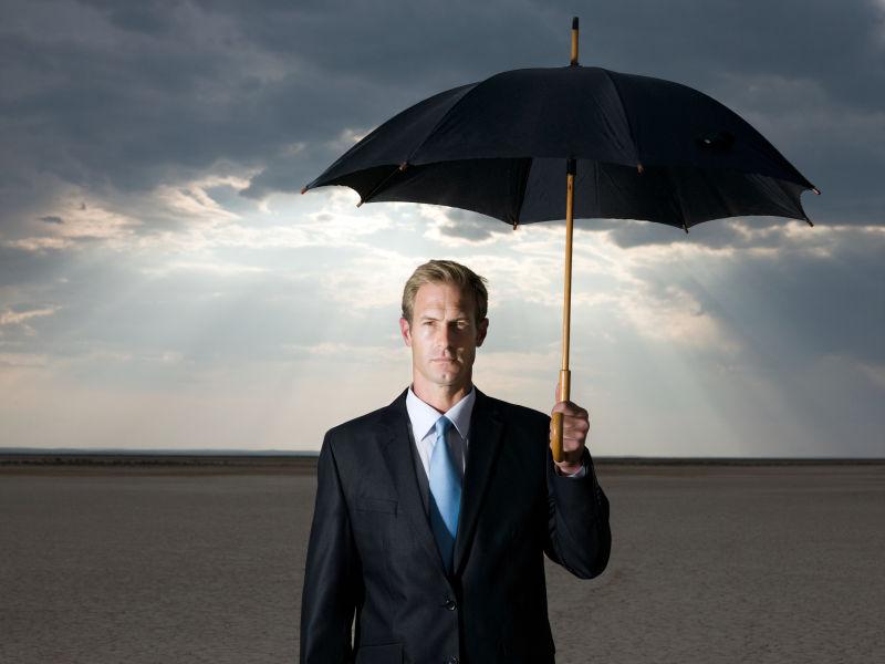 干旱土地上打雨伞的商人