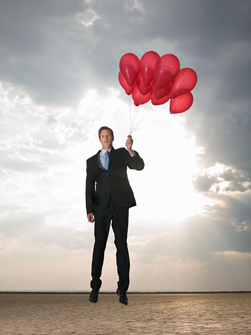 干旱土地上气球带着商人飞起来