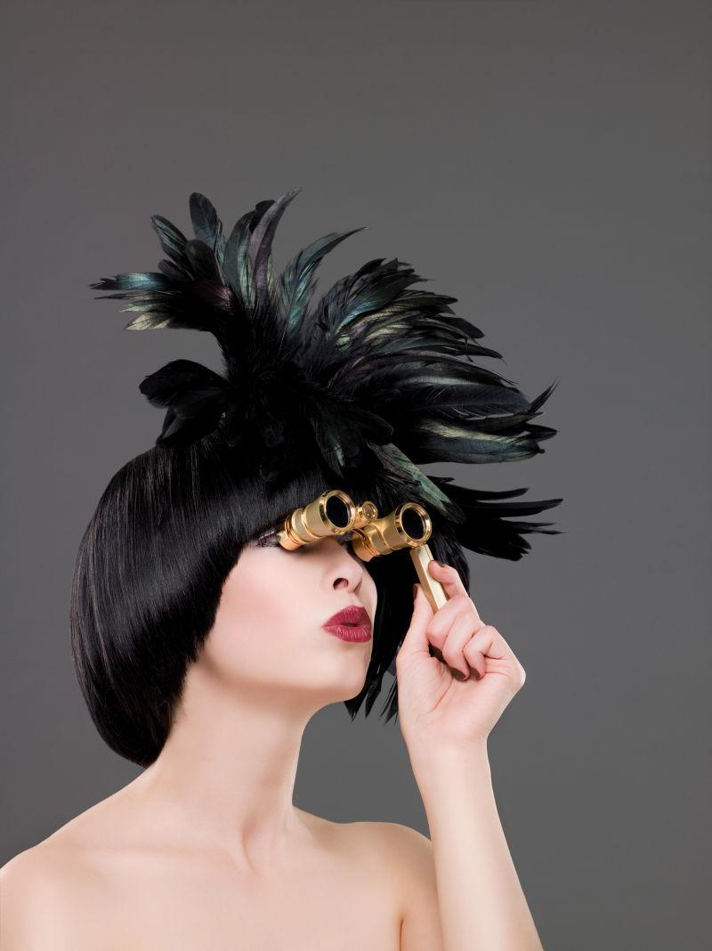 带着羽毛帽子的美女拿着老式望远镜