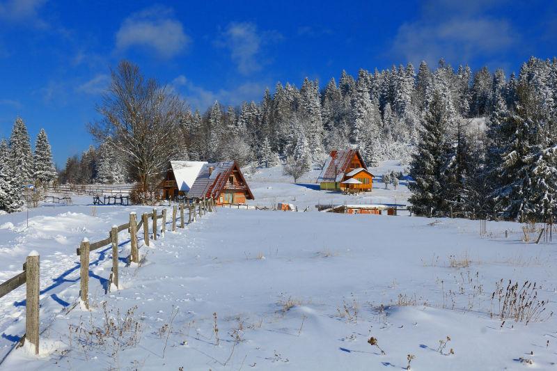 蓝天下冬天覆盖着雪的房子和山坡