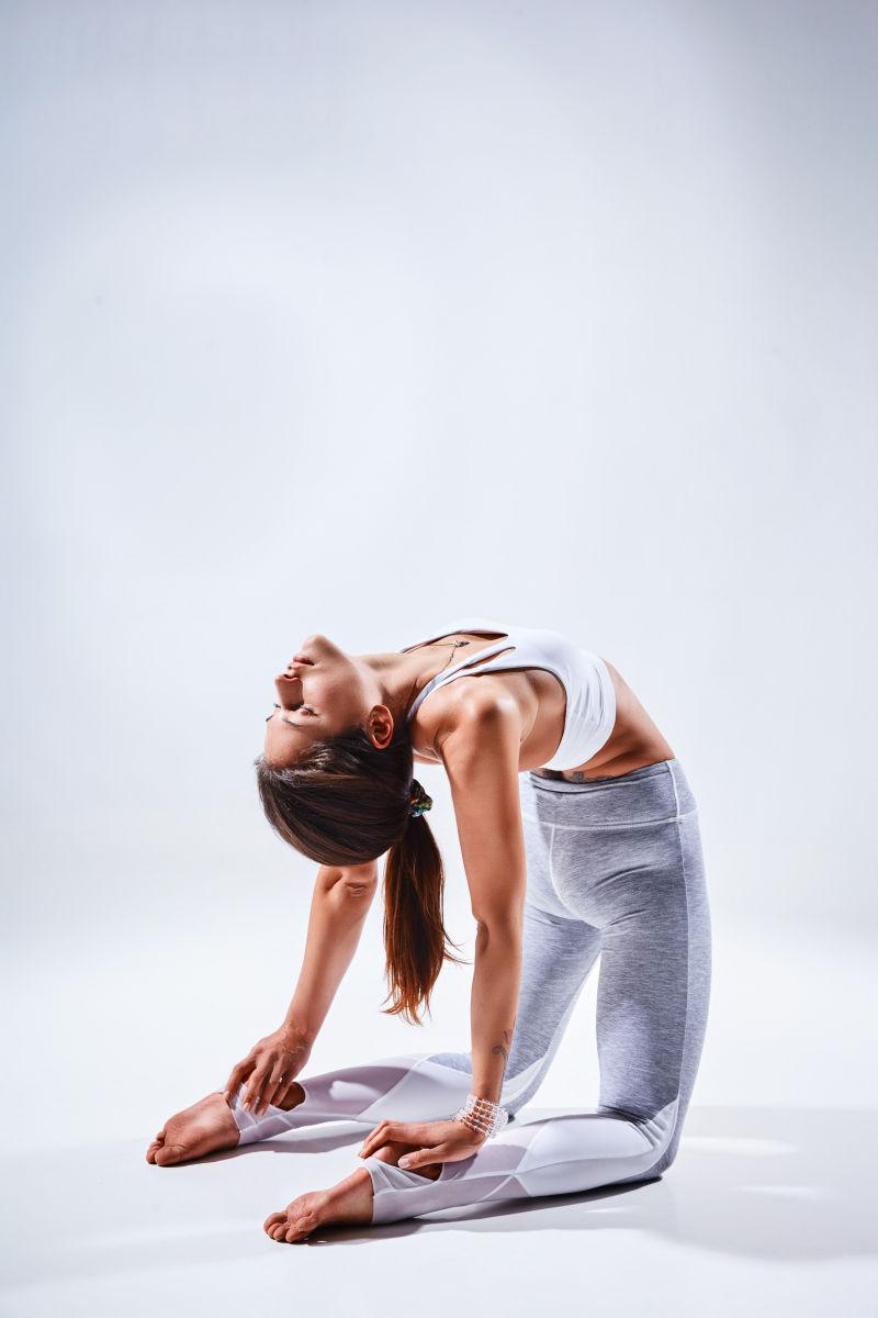 女人在白色背景下做瑜伽伸展腰部
