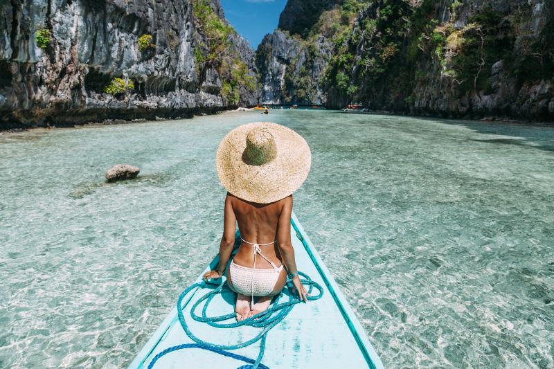 跪坐在淡蓝色小船上的比基尼美女