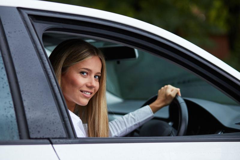 手握方向盘向窗外微笑的美女